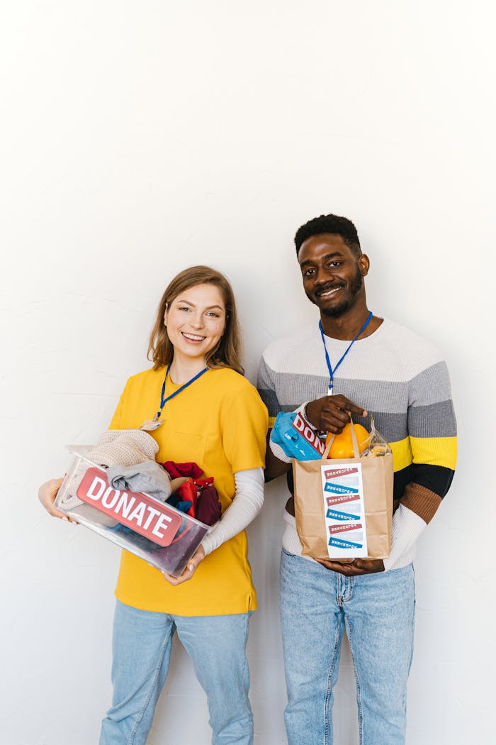 Smiling volunteers holding donation boxes against white background.
